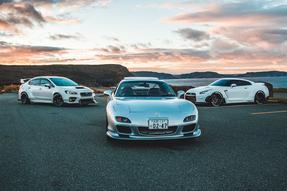 Three luxury sports cars parked outdoors with a stunning sunset backdrop